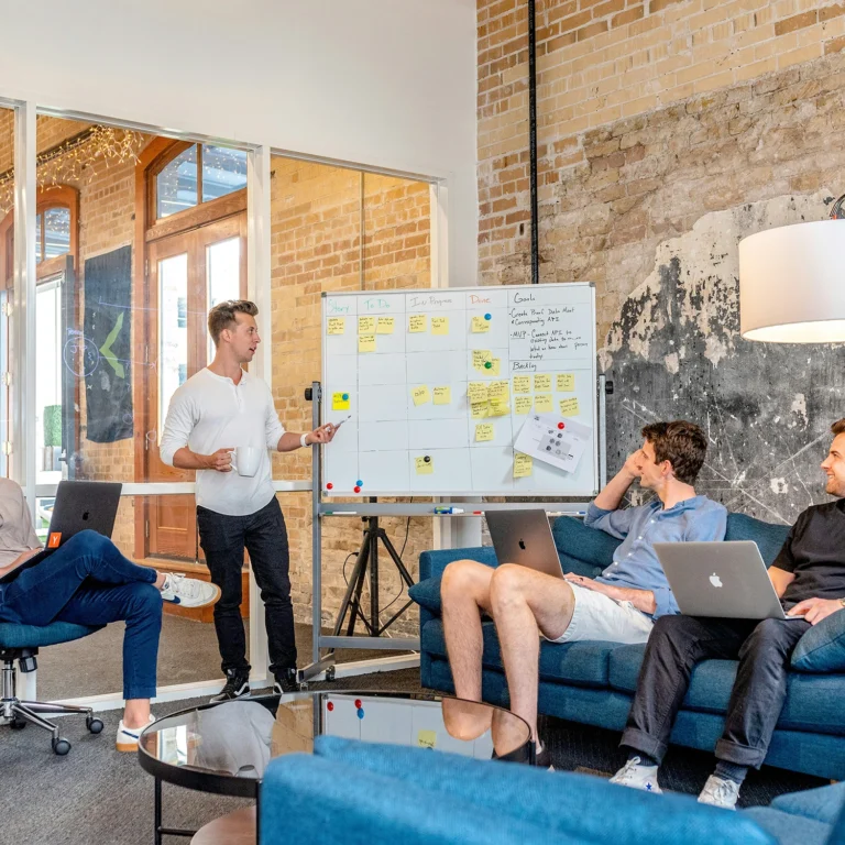 A group of coworkers collaborating in a focus group, sharing information on a whiteboard.
