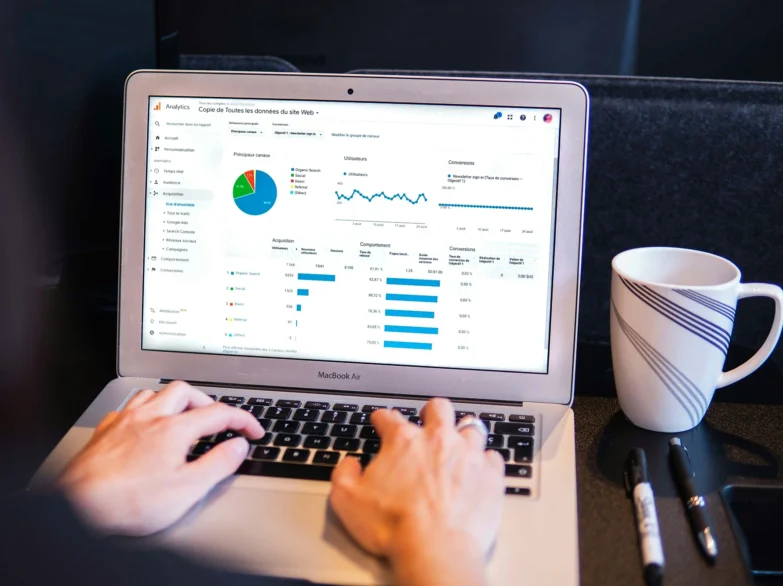 A person working on a laptop displaying a colorful graph, focused on Google analytics.
